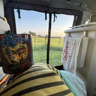 A person holding a mug in the back of a van.