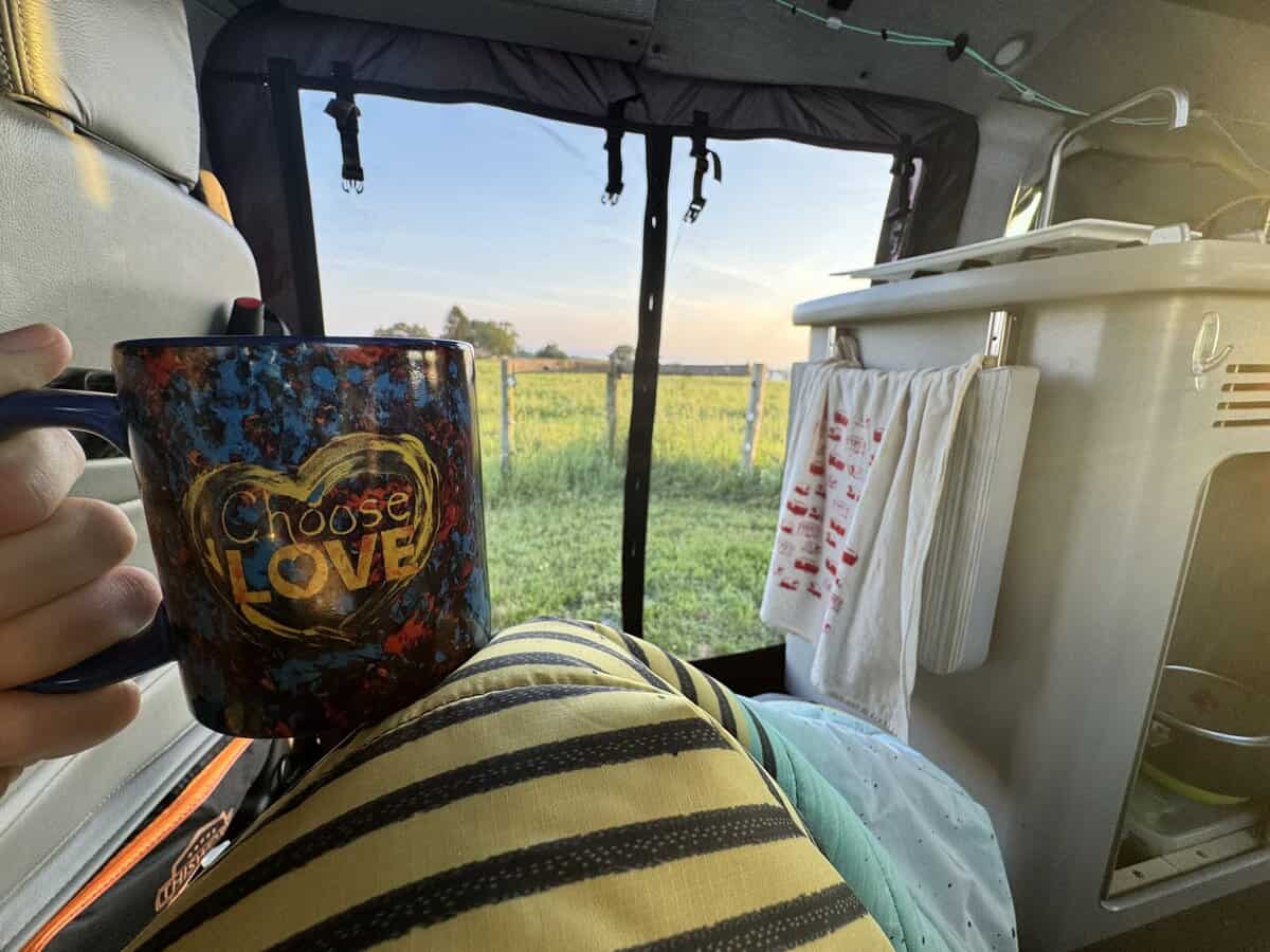 A person holding a mug in the back of a van.